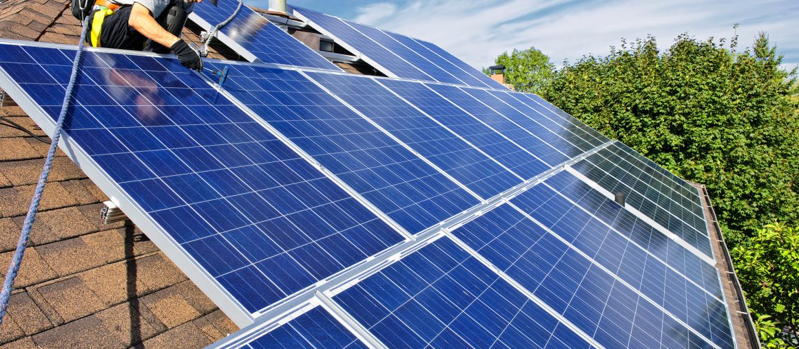 Man installing alternative energy photovoltaic solar panels on roof